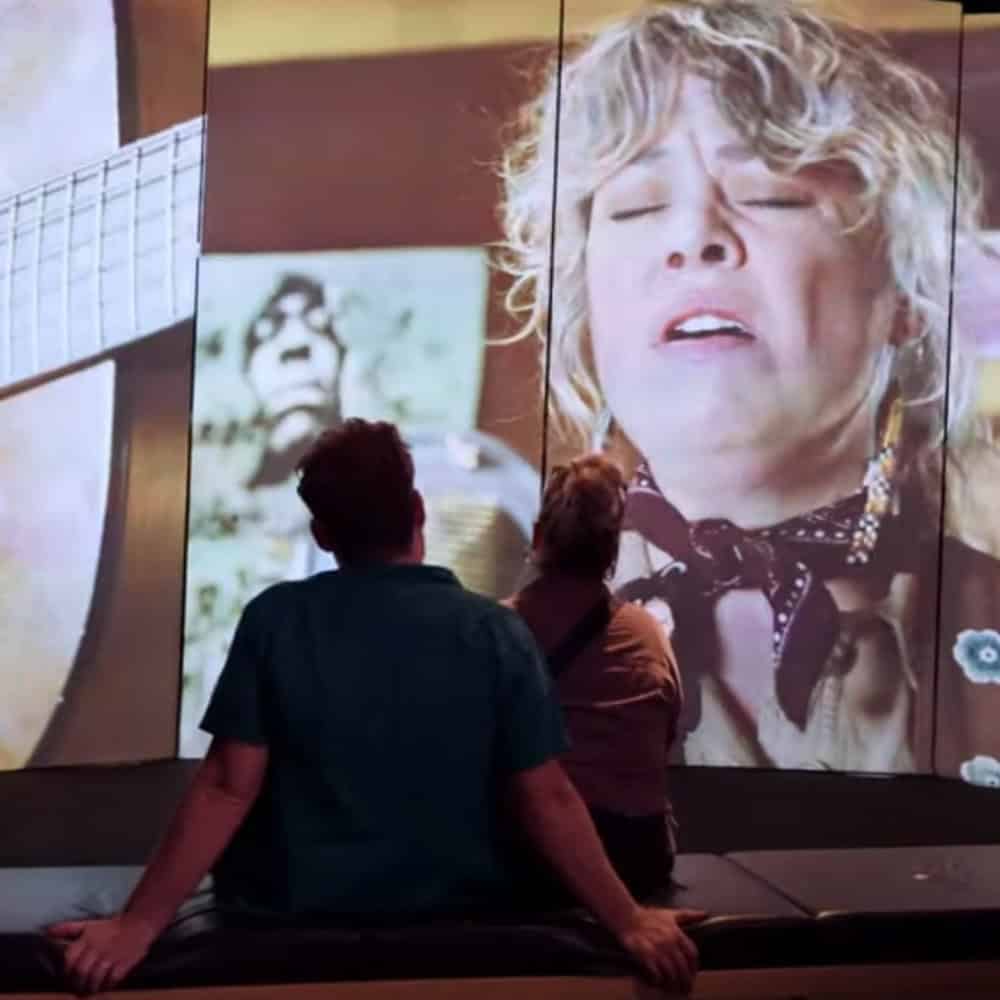 People looking at a musician on screen